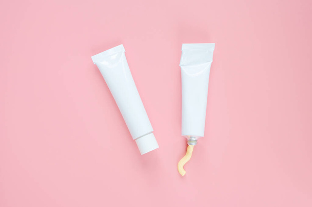 White cosmetic tubes on a pink background. Concept of face and body skin care, cosmetics. Top view, minimalism, flat lay, copy space. - Fotoğraf, Görsel