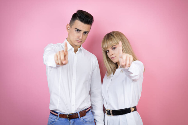 Giovane coppia di fidanzata e fidanzato su isolato sfondo rosa mostrando e indicando con le dita numero uno, mentre è grave - Foto, immagini