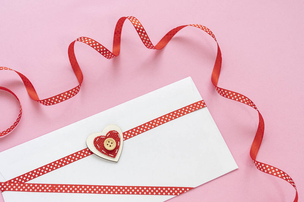 A letter card and red ribbon with polka dots on pink background - Photo, Image