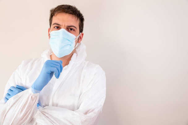 An adult male doctor wearing personal protective equipment and standing against a wall - COVID-19 - Photo, Image