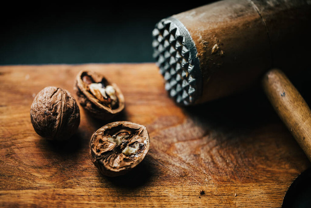 A topfview of the walnut breaking process with a wooden mallet - 写真・画像