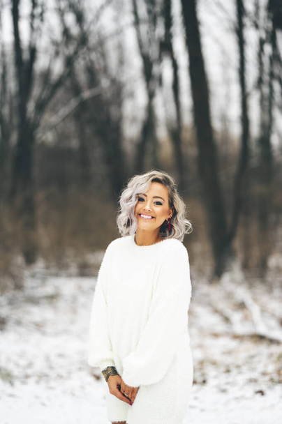 A sexy young female wearing a white sweater dress outdoors in winter - Fotoğraf, Görsel