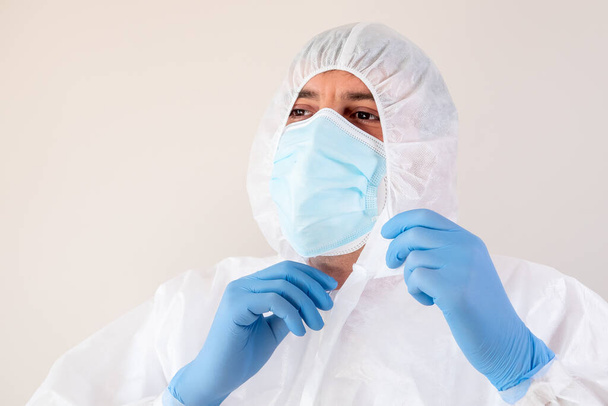 Um médico vestindo equipamentos de proteção individual e fixando sua máscara facial - COVID-19 - Foto, Imagem
