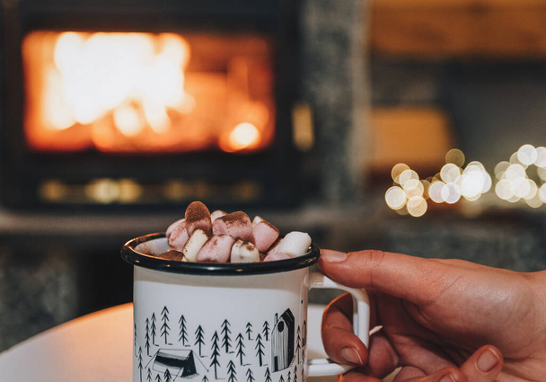 A hand holding a mug of cocoa or hot chocolate with powdered marshmallows on top - Foto, immagini