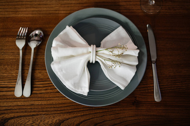 beautiful table setting. napkin in the form of a bow with dried flowers on plate - Photo, Image