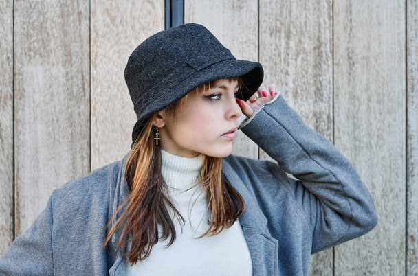 A Portrait young pretty Caucasian girl, dressed in a gray jacket, a white sweater and a hat. - Foto, imagen