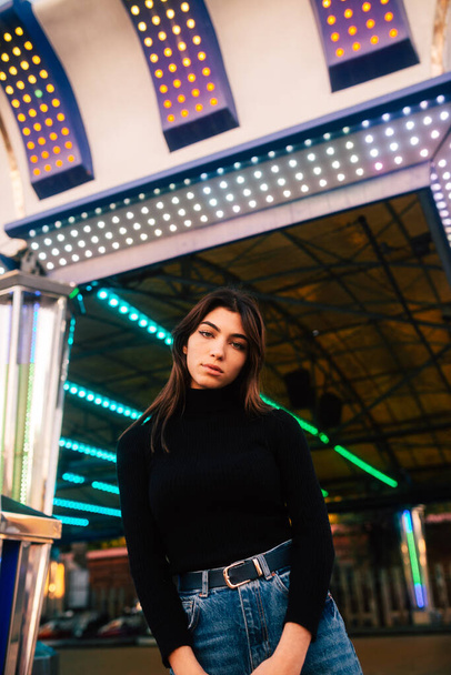A beautiful Caucasian girl wearing a black turtleneck and posing in the amusement park - Foto, afbeelding