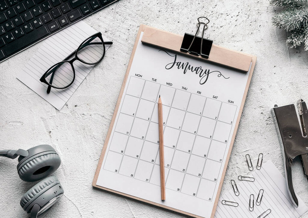 The flat lay of motivation and planning concept - a calendar diary, glasses, clips, stapler, headphones, keyboard, and pencil - 写真・画像