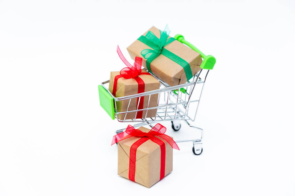 Small grocery cart with gift boxes on white background. Gifts for Valentines day, Christmas and birthday. Shopping online. Holiday sales and discounts for New year. Retail and wholesale purchases. - Fotografie, Obrázek