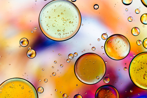 A macro shot of different sized bubbles on a colorful background - Foto, Bild