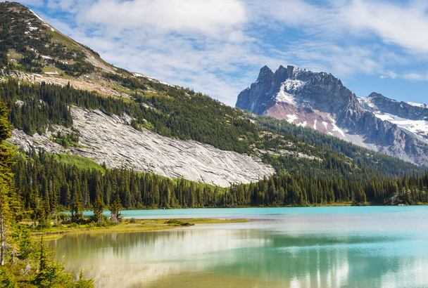 Спокойная сцена у горного озера с отражением скал в спокойной воде. - Фото, изображение