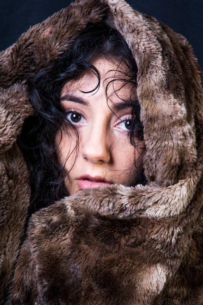 Portrait of a beautiful woman  with a fur blanket on black background - Fotoğraf, Görsel