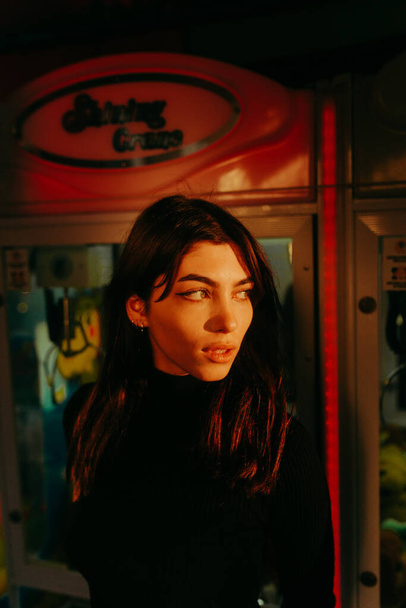 A beautiful Caucasian girl wearing a black turtleneck and posing in the amusement park - 写真・画像