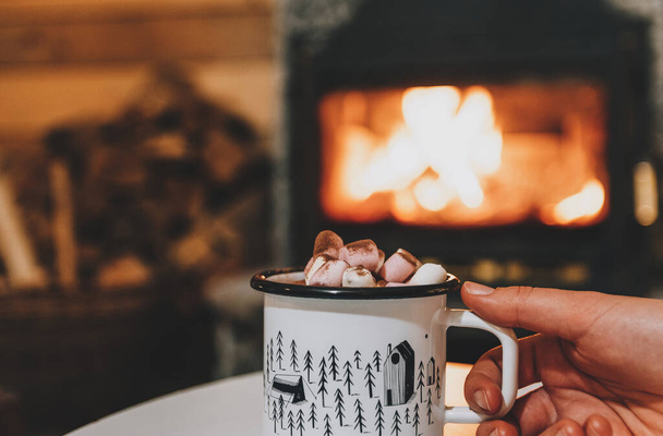 A hand holding a mug of cocoa or hot chocolate with powdered marshmallows on top - Foto, immagini