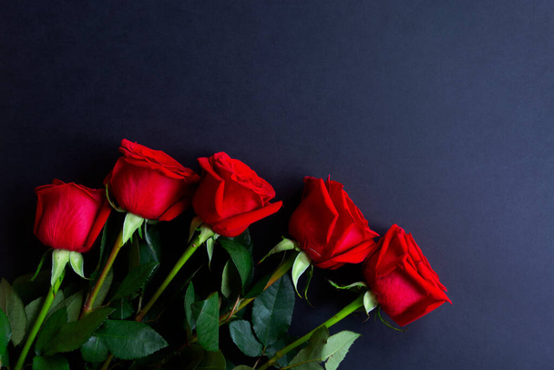 黒の背景に満開の新鮮な赤いバラのヒープを閉じます。花の束。コピースペース。トップビュー、フラットレイアウト。バレンタインデーや母の日、愛の概念. - 写真・画像