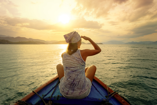 Mujer viajando en barco al atardecer entre las islas
 - Foto, imagen