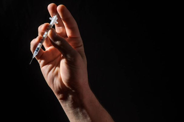 Hand with injection syringe on black background - Fotó, kép