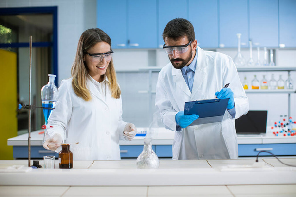 Jóvenes investigadores haciendo experimentos con humo en una mesa de un laboratorio químico - Foto, imagen