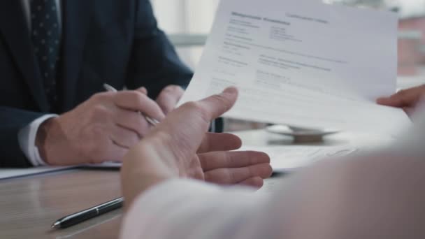Close-up of female hands passing over paper with resume to unrecognizable business person wearing formal suit, sitting in front of candidate - Footage, Video