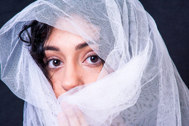 Portrait of a beautiful woman with white veil on black background - Foto, imagen