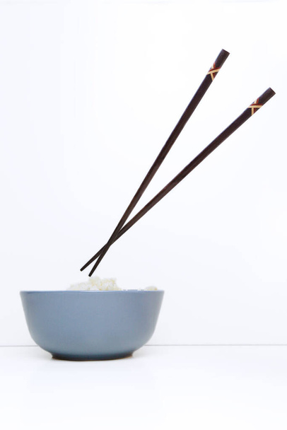 Schaal rijst met eetstokjes op wit tafelblad - Foto, afbeelding