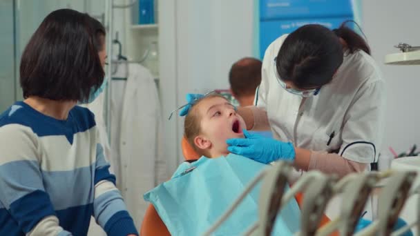 Pediatrische tandarts met masker behandelen tanden aan kleine meisje patiënt - Video