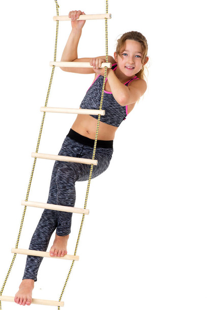 Girl performing gymnastic exercise on rope ladder. - Valokuva, kuva