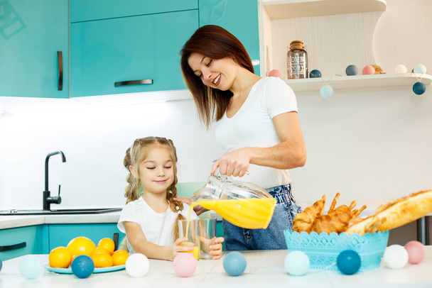 Onnellinen nuori äiti leipoo croissantia tyttärelleen keittiössä kotona. Onnelliset perhesuhteet - Valokuva, kuva