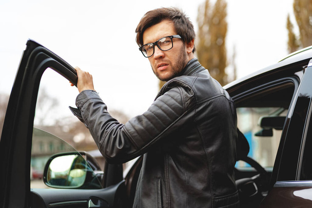 Stylish man in glasses sits in a car - Foto, imagen