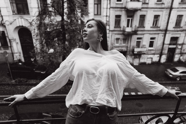 Fotózás egy gyönyörű lányról fehér ingben az erkélyen. - Fotó, kép