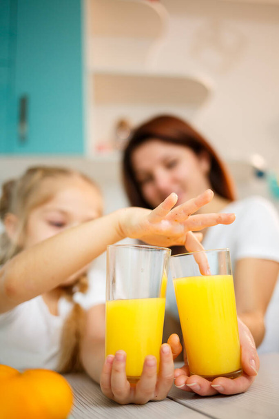 Äiti pieni tyttö juo appelsiinimehua, kun he syövät aamiaista yhdessä - Valokuva, kuva