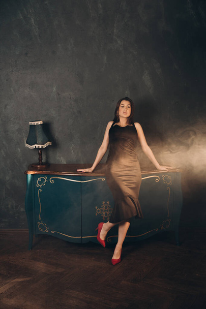 Fashion photoshooting in a photo studio of a beautiful girl in a black dress - Zdjęcie, obraz