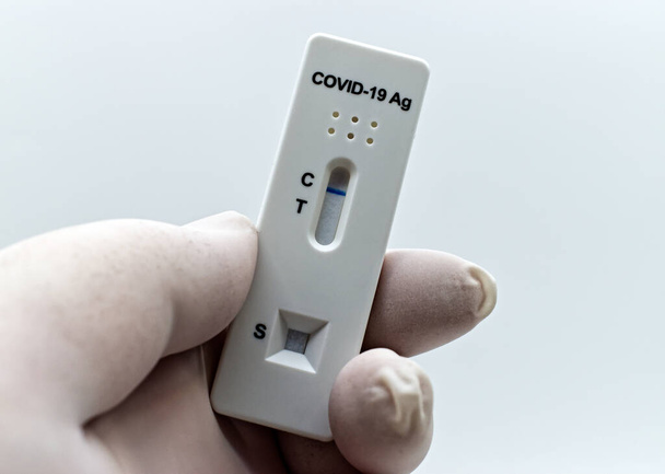 Γιατρός χέρι σε ελαστικό ιατρικό γάντι κρατώντας μια συσκευή ταχείας δοκιμής αντιγόνων για τη δοκιμή Covid-19. - Φωτογραφία, εικόνα