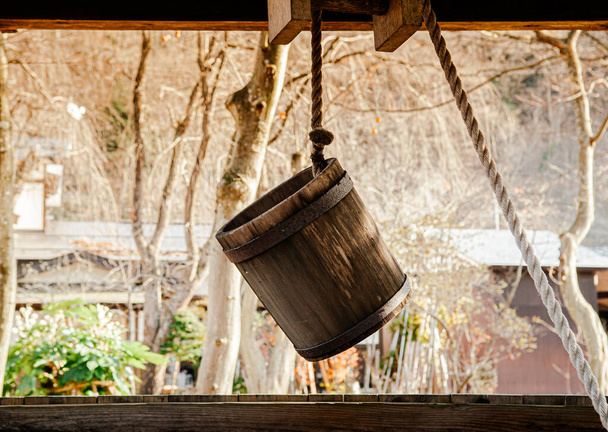 Old antique Water well wooden bucket with rope hanging above the hole - Photo, Image