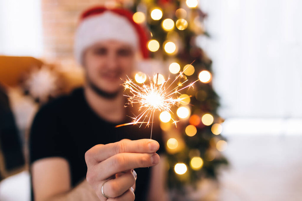 Man in red Santas hat with sparkler - Photo, image