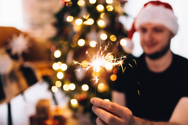 Man in red Santas hat with sparkler - Photo, Image