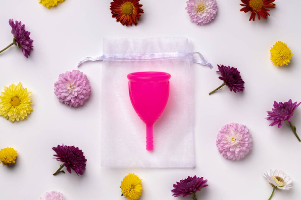 Menstrual cup on floral pattern background top view - Foto, Imagen