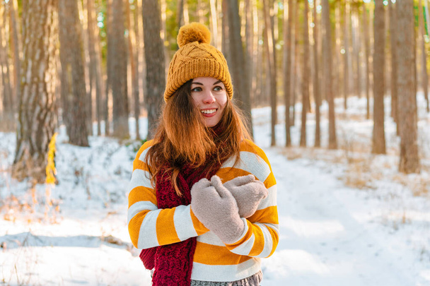 Portrét mladé ženy ve svetru na pozadí zasněžené krajiny v zimním borovicovém lese - Fotografie, Obrázek