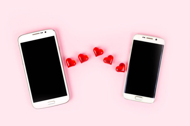 Teléfono móvil con pantalla negra y corazón rojo aislado sobre fondo rosa pastel. Vista superior, plano, espacio de copia. Día de San Valentín, amor, tecnología, concepto de citas en línea. - Foto, Imagen