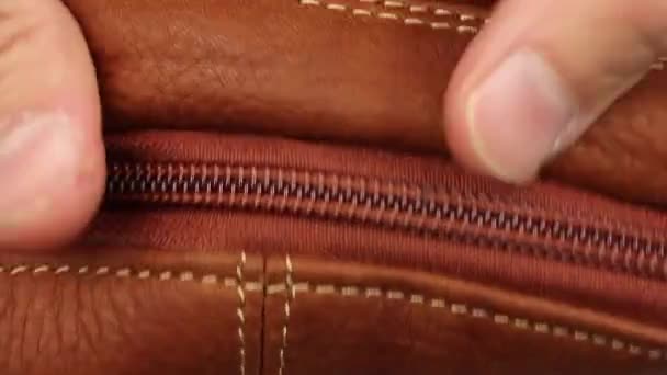 close-up zicht op hoe de mens hand testen licht bruin of rood natuurlijk glad mat leer met rits, buitenste deel en binnen, controle van de kwaliteit van het materiaal voor accessoires, macro - Video