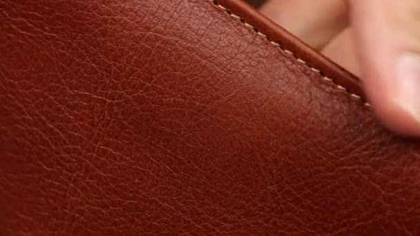 menselijke vinger testen textuur van bruin of rood natuurlijk glad mat luxe leer, controleren kwaliteit van mode-accessoires materiaal, cognac of brandy kleur, close-up macro-view - Video