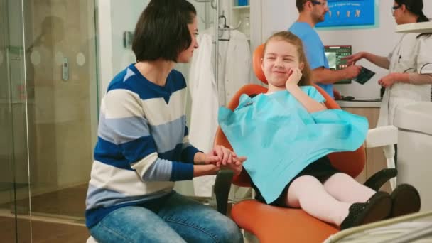 Droevig kind met een aangetaste massa aan haar moeder zittend in een stomatologische stoel - Video