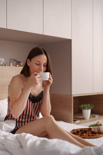 Mujer beber café en la cama con regalos - Foto, imagen