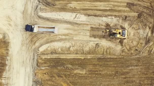 Letecký pohled shora dolů na bagr nakládající rozdrcený kámen do skládkového náklaďáku v kamenolomu - Záběry, video