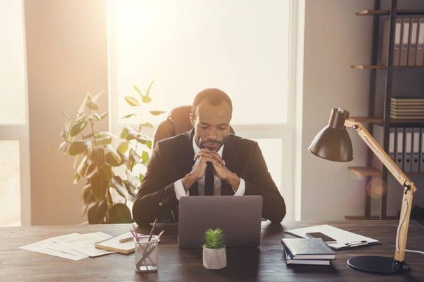 Портрет сосредоточены афро-американский мужчина маркетолог менеджер сидеть стол работы ноутбук решить запуск решение чувствовать себя вдумчивый смокинг костюм носить на рабочем месте - Фото, изображение