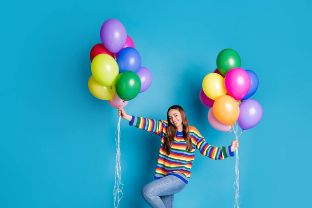 Photo of pretty charming girl feel pleasure close eyes hold many balloons wear good look mood clothes isolated over blue color background - Fotografie, Obrázek