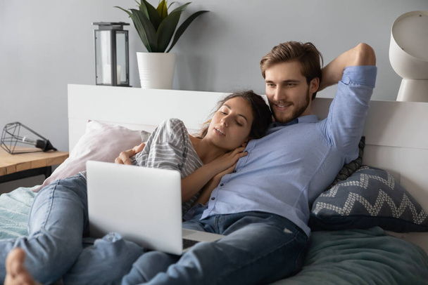 Happy couple cuddle in bed watching laptop - Fotoğraf, Görsel