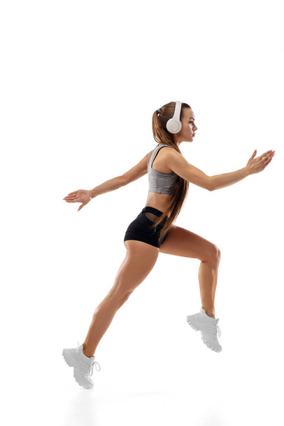 Caucasian professional female runner, athlete training isolated on white studio background. Copyspace for ad. - Foto, imagen