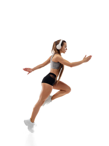 Caucasian professional female runner, athlete training isolated on white studio background. Copyspace for ad. - Zdjęcie, obraz