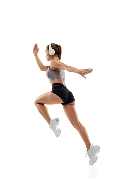 Caucasian professional female runner, athlete training isolated on white studio background. Copyspace for ad. - Zdjęcie, obraz